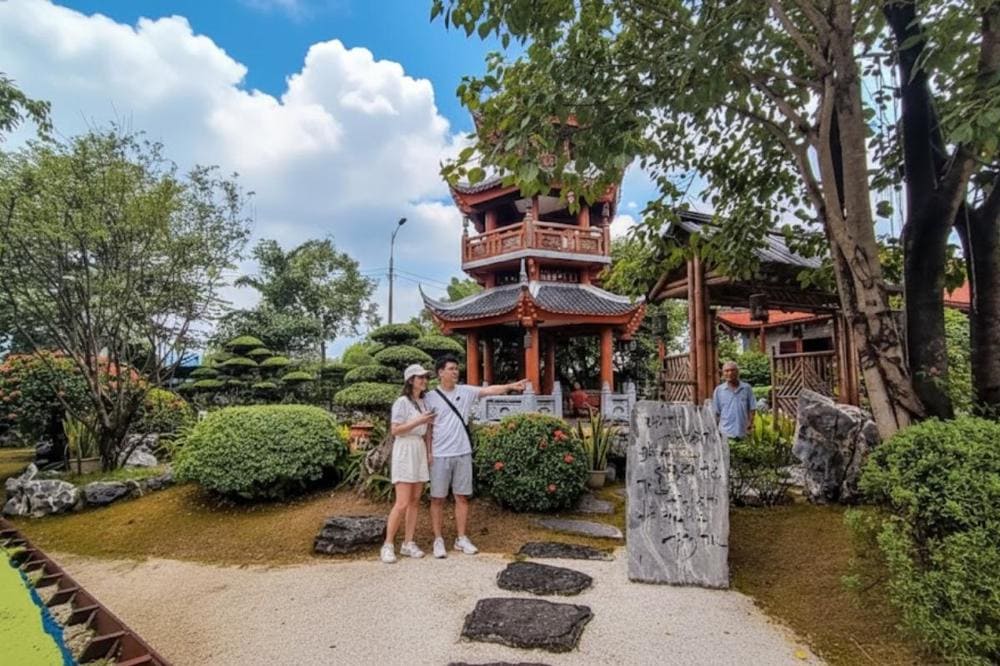 Lầu chuông ba tầng nổi bật giữa vườn thiền, lối đi đá tự nhiên uốn lượn qua những khóm cây được cắt tỉa cẩn thận.